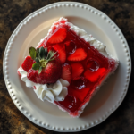 Moist slice of Strawberry Poke Cake with whipped topping and strawberries